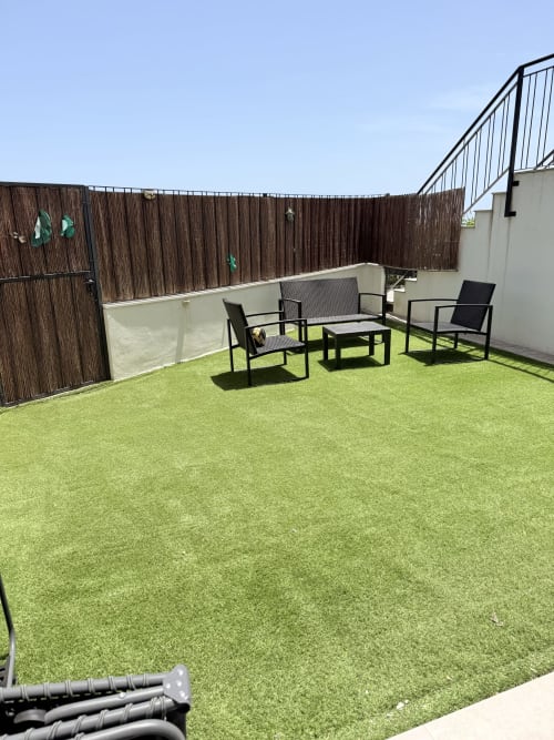 Terraza en la azotea con césped artificial, zona de descanso y paneles de privacidad marrones en la cabaña Sinese Design Homes