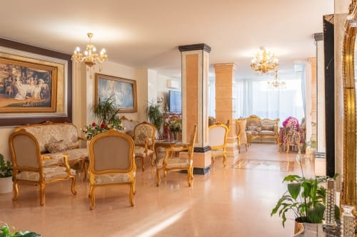 Hall d'entrée élégant de l'Hôtel Royal Paris Ivry avec mobilier doré, lustres et sol en marbre