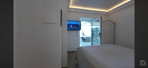 Modern bedroom at Villa D'Alessandro with sea view, flat-screen TV, and private balcony overlooking Anacapri
