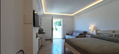 Modern bedroom at Villa D'Alessandro in Anacapri with double bed, flat-screen TV, kitchenette, and private balcony with sea