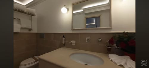 Modern bathroom with brown tile, white sink, toilet, and illuminated mirror in Villa D Alessandro private apartment, Anacapri
