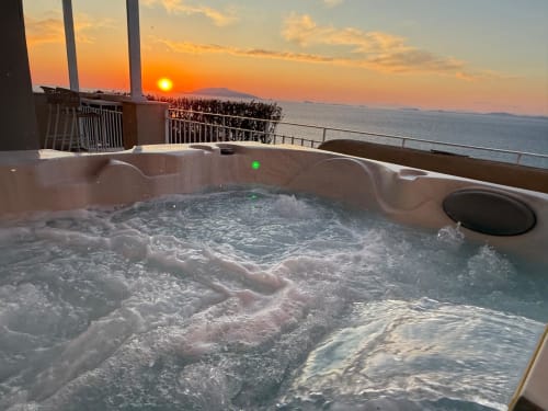 Bubbling jacuzzi on sunset-lit balcony overlooking Capri sea at Villa D'Alessandro, Anacapri
