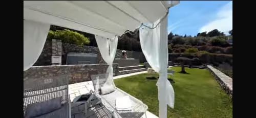 White pergola with flowing curtains on sea view terrace at Villa D Alessandro, Anacapri, overlooking lush gardens and