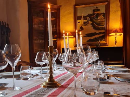 Table élégante à Domaine de Labrousse avec ambiance aux chandelles, verres de vin et tableaux encadrés en Périgord