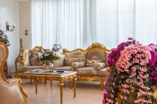 Élégant salon de l'Hôtel Royal Paris Ivry avec mobilier doré orné, fleurs roses et décor parisien raffiné