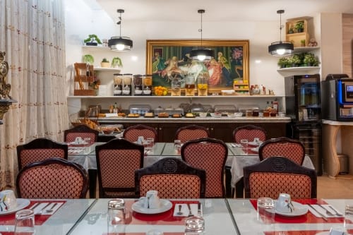 Salle à manger élégante de l'Hôtel Royal Paris Ivry avec chaises rouges à motifs, éclairage moderne et décoration murale