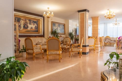 Élégant hall du Hôtel Royal Paris Ivry avec mobilier doré, lustres en cristal et sols en marbre.