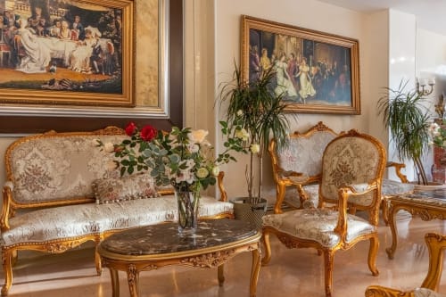 Salon élégant de style néoclassique à l'Hôtel Royal Paris Ivry avec meubles dorés, table en marbre et tableaux d'époque