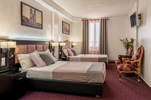 Suite Deluxe Hotel Royal Paris Ivry avec deux lits, tête de lit rose, moquette bordeaux et œuvres d'art parisiennes