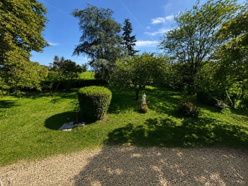 Jardins de prestige du Château Alto Cormeil à Saint-Émilion avec haies topiaires, arbres centenaires et un hôte en promenade