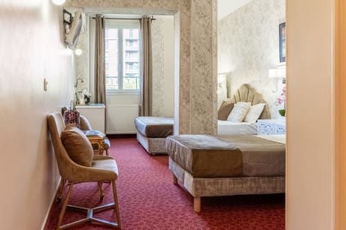 Triple Deluxe room at Hotel Royal Paris Ivry with twin beds, leather chair, and Parisian-style decor