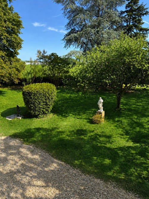 Jardin verdoyant du Château Alto Cormeil à Saint-Émilion avec pelouse impeccable, haies et statue blanche