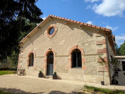 Bâtiment historique en pierre du Domaine Alga B&B à Bourg-Charente avec accents en terre cuite et fenêtres en arc