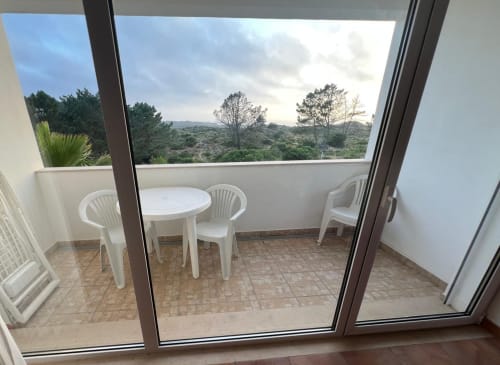 Balcony view from Casa Dourada villa in Aljezur with white furniture overlooking green hills