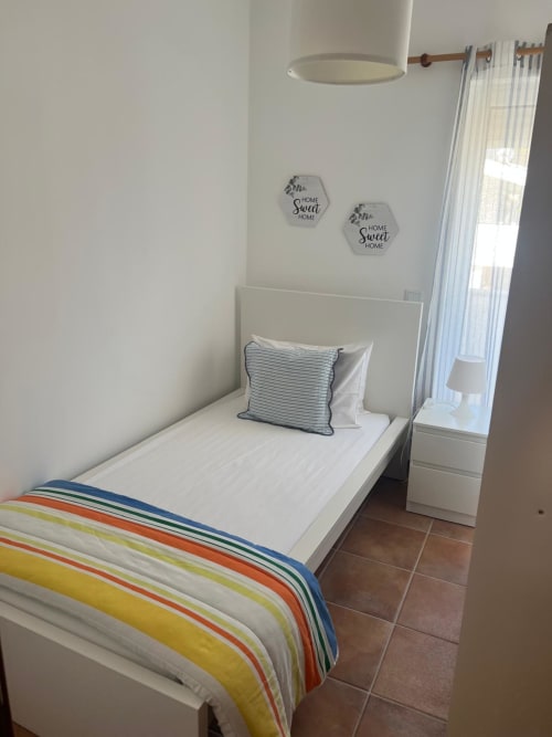Bright bedroom at Casa Dourada villa in Aljezur with single bed, striped bedding, and sea view curtains