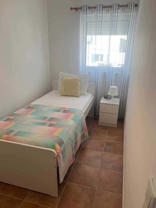 Bright bedroom in Casa Dourada villa, Aljezur with single bed, colorful quilt, striped curtains and sea view
