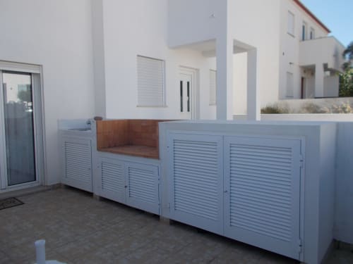 Modern white villa patio with louvered storage cabinets and wooden bench seating at Casa Dourada, Aljezur Portugal