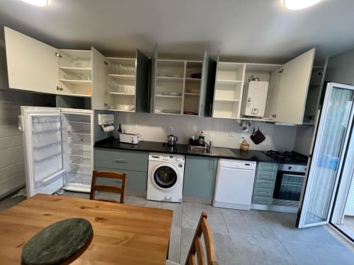Modern kitchen in Casa Dourada villa, Aljezur with gray cabinets, black countertops, appliances and wooden dining table