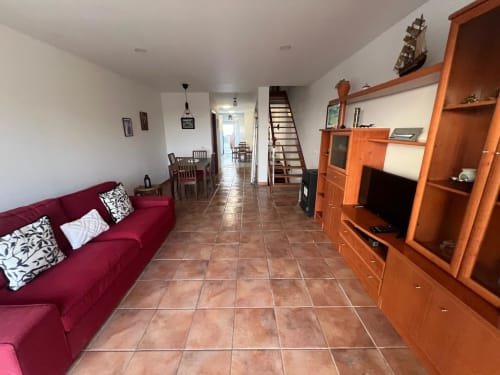 Spacious open-plan living room in Casa Dourada villa with burgundy sofa, wooden entertainment unit, tiled floor, dining area