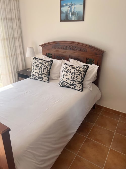 Elegantly appointed bedroom with wooden headboard, white linens, and patterned pillows at Casa Dourada villa in Aljezur,