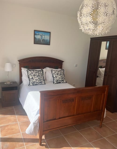 Elegantly furnished bedroom at Casa Dourada villa in Aljezur with wooden bed, white linens, and decorative chandelier