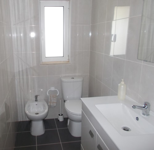 Modern bathroom in Casa Dourada villa, Aljezur with white tiles, toilet, bidet, sink, mirror and window