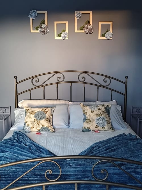 Elegant bedroom at Agriturismo Marinello in Pienza with ornate metal bed, blue bedding, and decorative wall frames