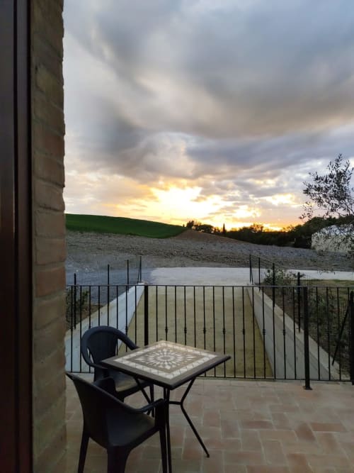 Sunset view from patio at Agriturismo Marinello in Pienza with table, chairs, and countryside landscape