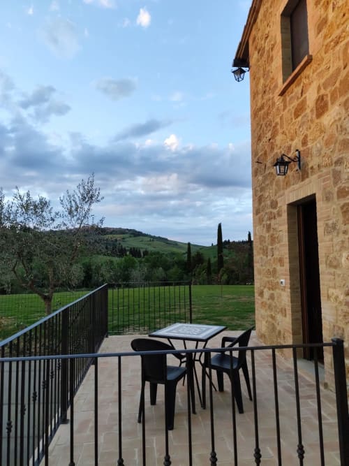 Tuscan villa patio at Agriturismo Marinello in Pienza with dining table, rolling green hills, cypress trees, and stone