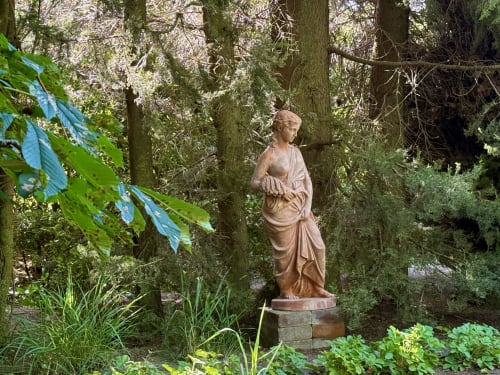 Statue en terre cuite au cœur d'un jardin verdoyant du Domaine de Montlaur, Val-de-Dagne, entourée d'arbres