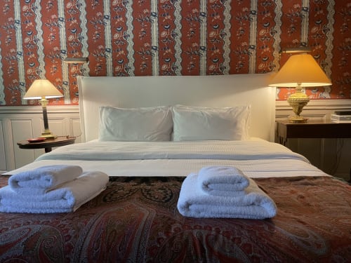 Chambre luxueuse au Domaine de Montlaur avec serviettes douces, literie crème et élégant papier peint rayé à Val-de-Dagne