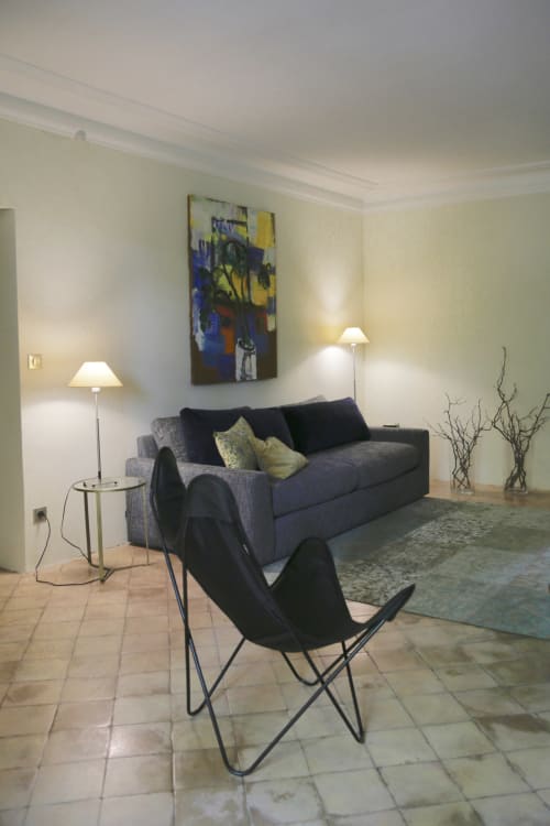 Salon moderne du Domaine de Montlaur avec canapé gris, fauteuil papillon noir, œuvre contemporaine et décoration