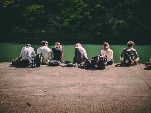 Group of travelers sitting together by a scenic green lake at Domaine Alga guesthouse in Bourg-Charente