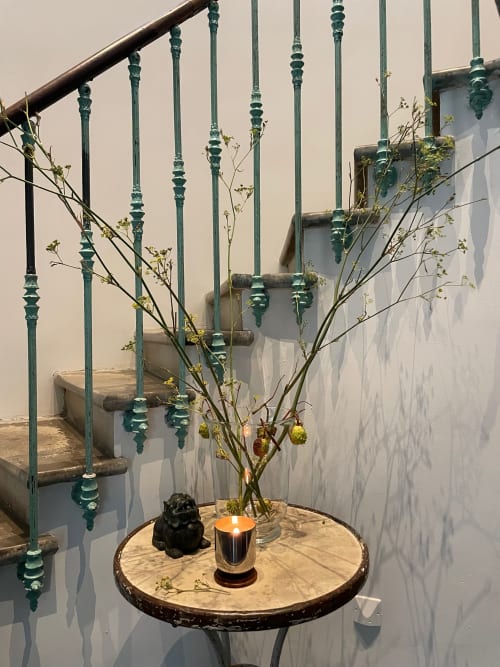 Table décorée en bois avec branches, bougie et sculpture dans le couloir du gîte Domaine de Montlaur avec rampes vertes