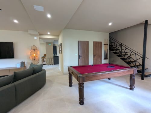 Salle de loisirs moderne au Domaine Alga avec billard, canapé courbe et escalier à Bourg-Charente