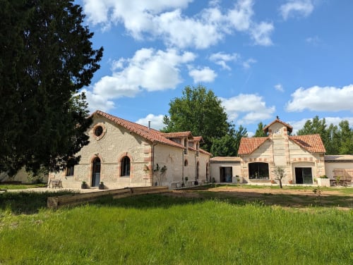 Domaine Alga, manoir en pierre rustique au toit en terre cuite à Bourg-Charente, France, entouré de prés verdoyants et d'arbres