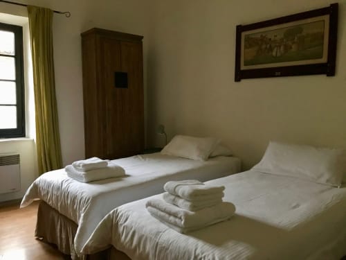 Lits jumeaux aux draps blancs et serviettes pliées à La Maison du Village, Domaine de Montlaur, Val-de-Dagne