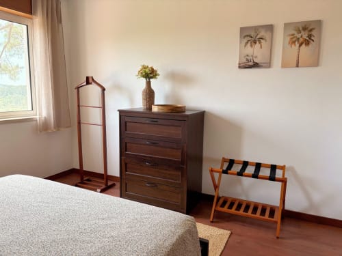 Quarto da Quinta Vale da Paz B&B em Azambuja com cômoda de madeira, suporte para bagagens e arte de palmeiras