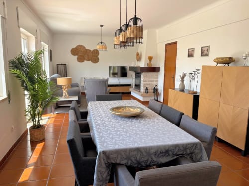Sala de jantar da Quinta Vale da Paz em Azambuja com mesa, cadeiras cinzentas, móveis de madeira e luminárias pendentes