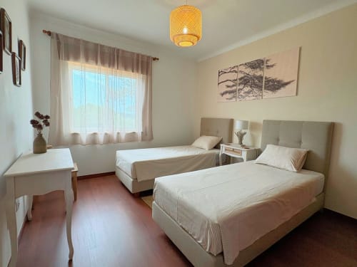 Quarto duplo na pousada Quinta Vale da Paz em Azambuja com duas camas, cabeceiras bege, janela e piso de madeira
