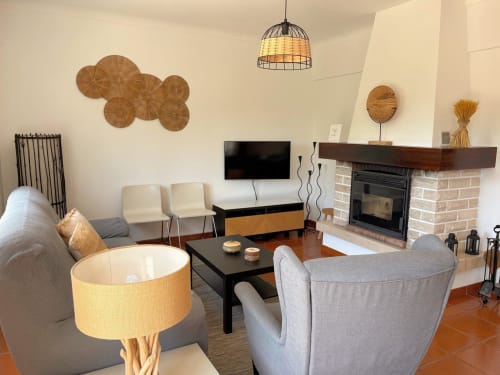 Sala de estar aconchegante da Quinta Vale da Paz em Azambuja com lareira, assentos confortáveis e decoração acolhedora