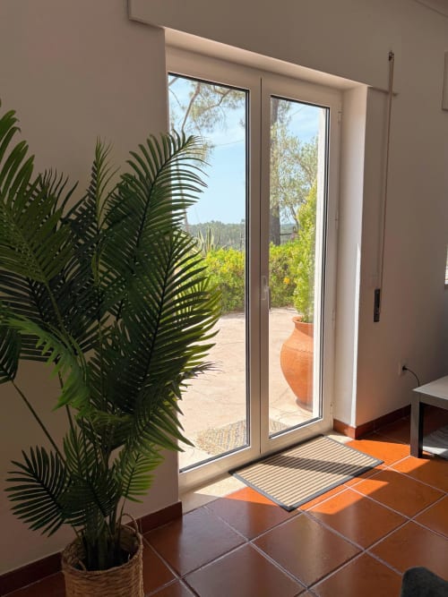 Portas de pátio com vista para o jardim da boutique hotel Quinta Vale da Paz em Azambuja, Portugal, com planta de palmeira e vaso de terracota