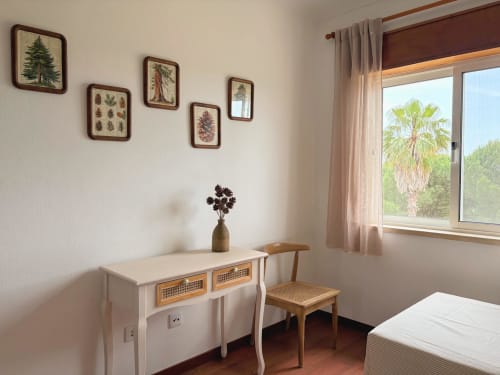 Quarto aconchegante da Quinta Vale da Paz em Azambuja com escrivaninha, cadeira, arte botânica na parede e vista para palmeiras