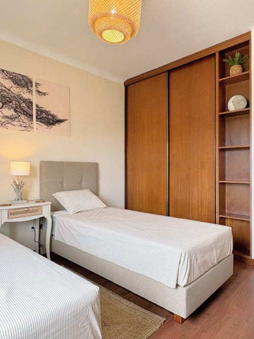 Quarto moderno da Quinta Vale da Paz com camas gêmeas, guarda-roupa de madeira e luminária de teto trançada em Azambuja