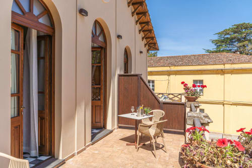 Deluxe room balcony at Albergo Al Cinghiale with terracotta tiles, wooden furniture, red flowers, and arched doors