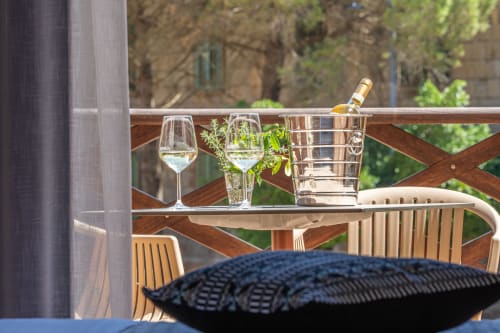 Elegant balcony at Albergo Al Cinghiale with wine glasses, bottle chiller, and garden views in Guspini, Italy
