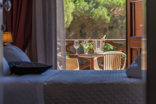 Balcony view at Albergo Al Cinghiale showing wine glasses and bottle with wooden chairs overlooking greenery