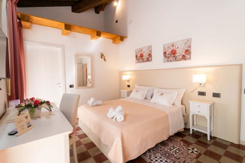 Spacious double room at Albergo Al Cinghiale with peachy bedding, modern amenities, and traditional terracotta tile floors
