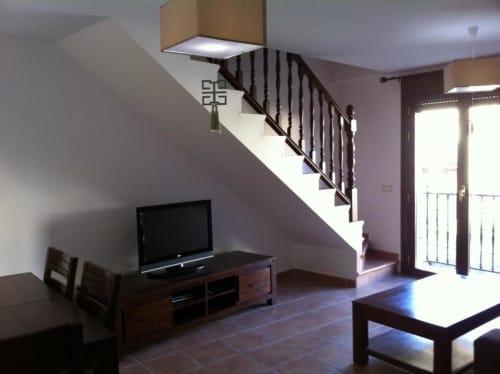 Sala de estar moderna en apartamento rural La Cabrera con escalera de madera, televisor de pantalla plana y acceso a patio abierto