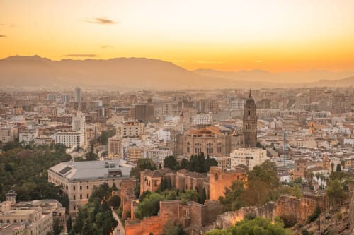 Atardecer dorado sobre el skyline de Málaga con la catedral y las montañas, vista desde el Hotel Balcón De Los Montés